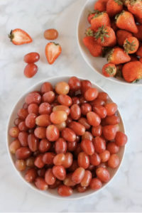 Bowl of red cherry tomatoes and bowl of red strawberries